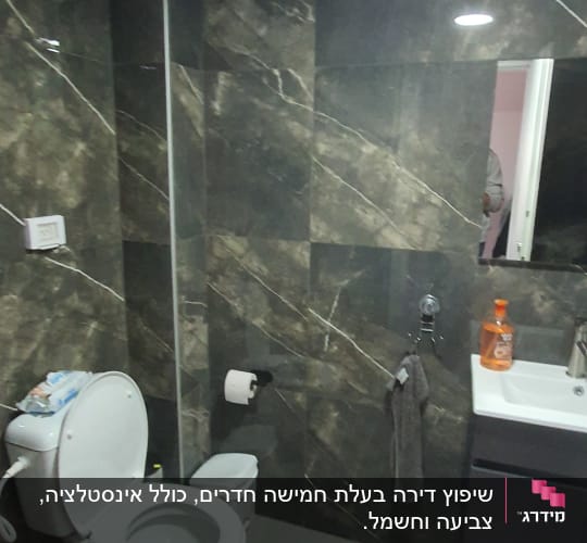 Bathroom with dark tiles, toilet, and sink.